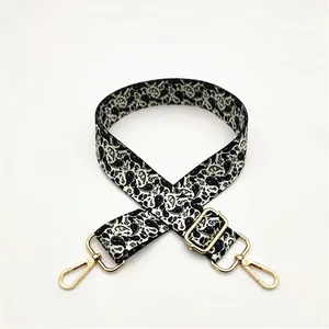 Detail of adjustable black and white paisley woven shoulder strap with gold hardware hooks