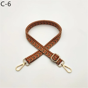 Detail of adjustable woven bag strap with orange and green chevron pattern and gold metal hooks