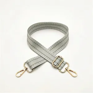 Close-up of adjustable fabric shoulder strap with grey and white geometric patterns and gold clips