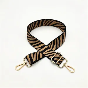 Detail of adjustable zebra print bag strap with golden metal swivel hooks and buckles