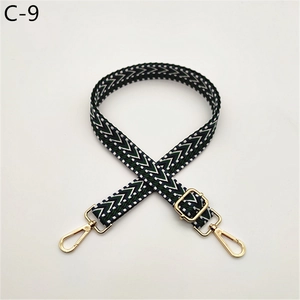 Macro detail of dark green and white herringbone webbing strap with gold swivel hooks