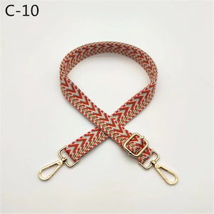 Detail of adjustable wide woven shoulder strap with geometric patterns and gold metal clasps