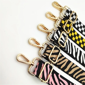 Detail of five adjustable handbag straps with zebra and checkerboard patterns and gold hooks