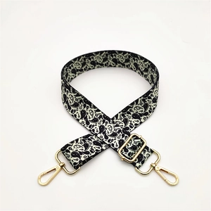 Adjustable black and white paisley patterned shoulder strap with gold metal buckles