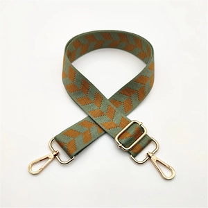 Detail of adjustable woven bag strap with green herringbone pattern and gold metal hooks