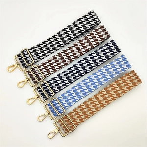 Détail de cinq bandoulières à motif pied-de-poule avec boucles métalliques dorées réglables
