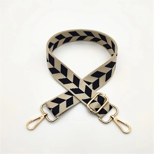 Close-up of adjustable strap with black arrow jacquard pattern and gold metal buckles