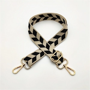 Close-up of beige woven bag strap with black geometric arrows and gold metal hardware