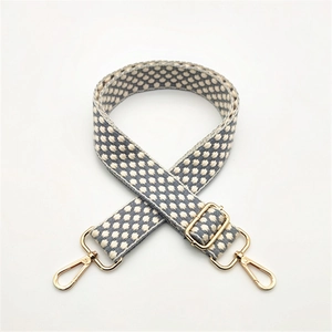 Close-up of adjustable woven shoulder strap with grey-blue pattern and gold metal hardware
