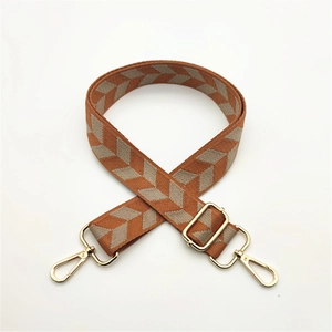 Detail view of woven guitar strap with orange herringbone pattern and gold metal hooks