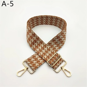 Détail d'une bandoulière en pied-de-poule ajustable avec mousquetons et boucle en or clair