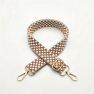 Close-up of thick woven brown polka dot bag strap with gold metal lobster clasps