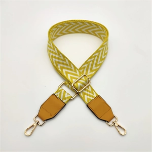 Detail of woven diamond pattern bag strap with brown leather and gold metal buckle