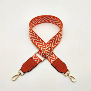 Detail of adjustable PU leather bag strap with orange and white V-shaped chevron pattern