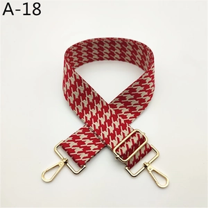 Détail d'une bandoulière de sac pied-de-poule rouge et blanc avec boucles dorées