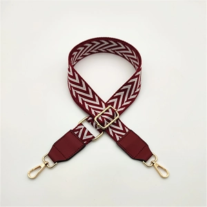 Detail of adjustable woven bag strap with wine red V-pattern and gold hardware