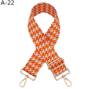 Détail de la bandoulière pied-de-poule orange et blanche avec boucles dorées réglables