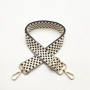 Close-up of woven bag strap with star pattern and adjustable gold metal lobster clasps