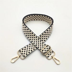 Detail of adjustable black and white geometric woven strap with gold metal hooks