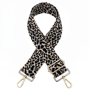 Detail of adjustable leopard print bag strap with golden metal snap hooks and buckles