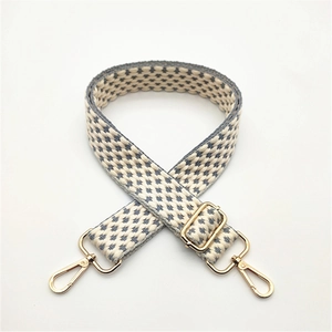 Close-up of adjustable gray and white woven shoulder strap with gold metal lobster clasps