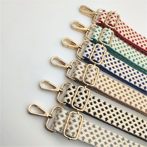 Detail of adjustable woven shoulder straps with geometric patterns and gold metal hooks