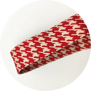 Gros plan sur la texture jacquard pied-de-poule rouge et blanc de la bandoulière
