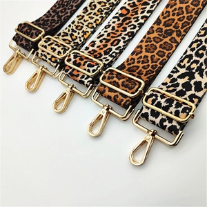 Close-up of five leopard print bag straps with golden metal hooks and buckles
