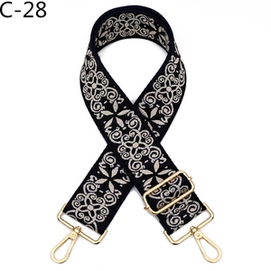 Detailed embroidery pattern on navy blue adjustable shoulder strap with gold metal buckle