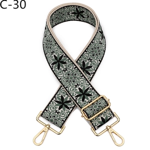 Detail of adjustable floral canvas bag strap with green pattern and gold metal buckles