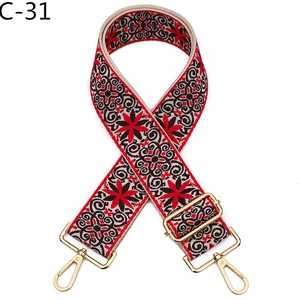Detail of ethnic embroidery bag strap with red floral patterns and gold metal hooks
