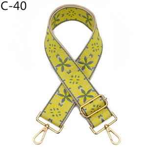 Close-up of yellow and green floral embroidery on wide crossbody strap with gold metal hooks