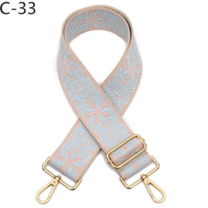 Detail of adjustable blue and pink floral woven bag strap with golden lobster clasps