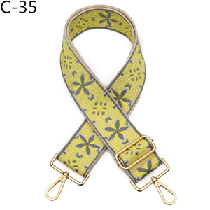 Close-up of adjustable jacquard bag strap with yellow floral patterns and gold hooks