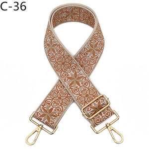 Close-up of ethnic floral embroidery patterns on wide adjustable bag strap with gold hooks