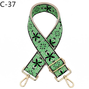 Close-up of green floral embroidery on bag strap with polished gold lobster clasps