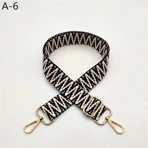 Detail of adjustable black and white woven shoulder strap with gold metal swivel hooks
