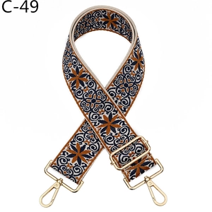 Close-up of wide ethnic jacquard bag strap with gold metal hooks and blue orange patterns