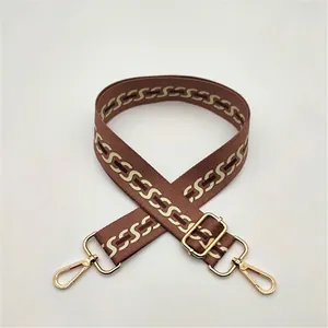Detail of adjustable brown shoulder strap with beige S-pattern weaving and gold hardware