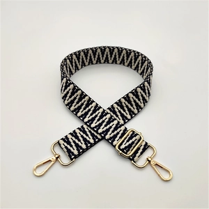 Close-up of adjustable woven shoulder strap with black white wave patterns and gold hardware