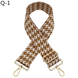 Detail of jacquard houndstooth strap with golden metal swivel hooks and adjuster