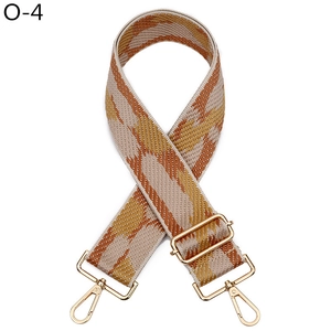Macro detail of geometric patterned bag strap with golden lobster clasps and buckle