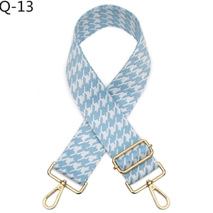 Detail of blue and white houndstooth woven strap with adjustable gold metal buckle