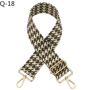 Detail of dark green houndstooth woven wide bag strap with luxury gold metal hooks