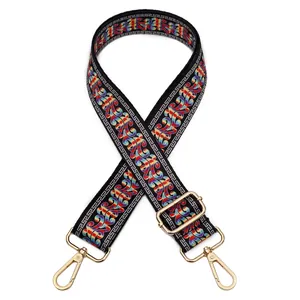 Detail view of ethnic embroidery on adjustable black bag strap with gold metal hooks