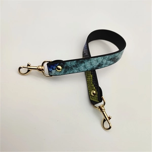 Detail of faux snakeskin purse strap with gradient green texture and gold lobster clasps