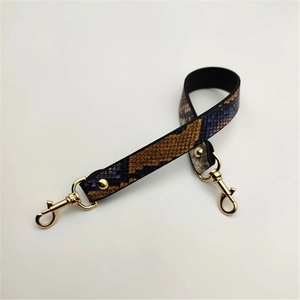 Detail of snake print replacement bag strap with golden lobster clasps and metal rivets