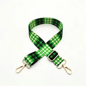 Detail view of green and white plaid adjustable strap with golden metal swivel hooks