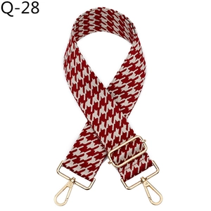 Detailed view of red and white houndstooth wide woven bag strap with gold metal hardware