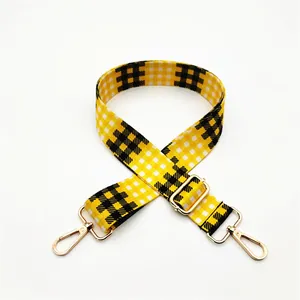 Detail view of yellow and black checkered bag strap with gold metal lobster clasp and buckle